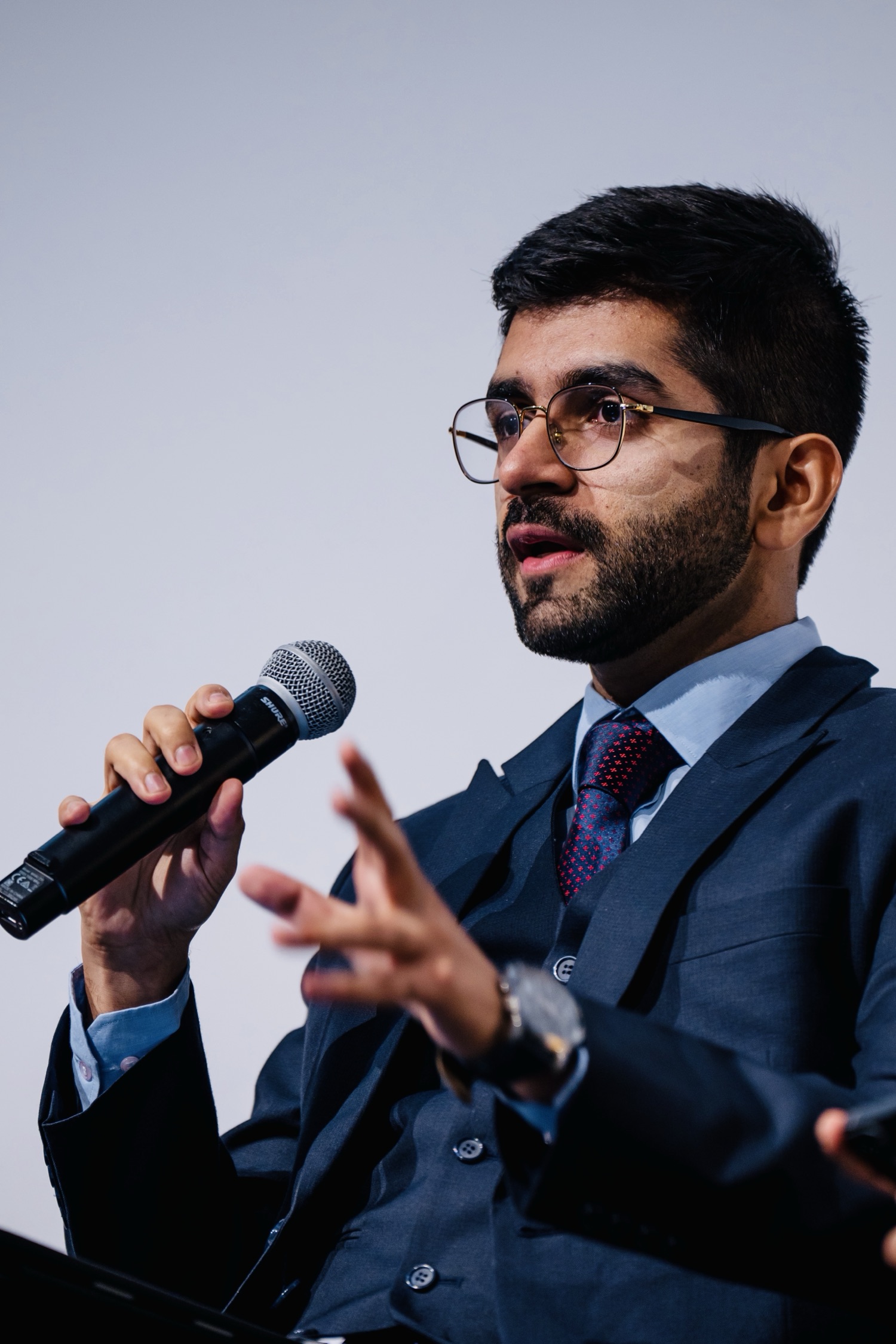 Kashish Aneja speaking with a microphone on a panel